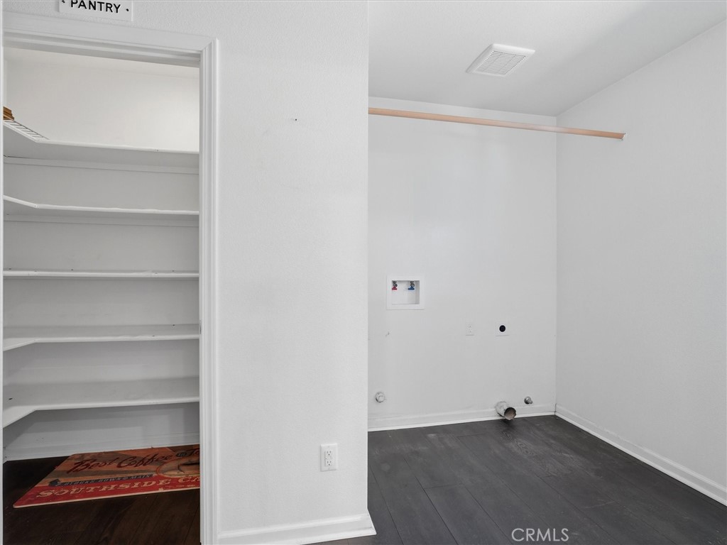 Laundry area with washer hookups and hanging rod beside a pantry with built-in shelves.