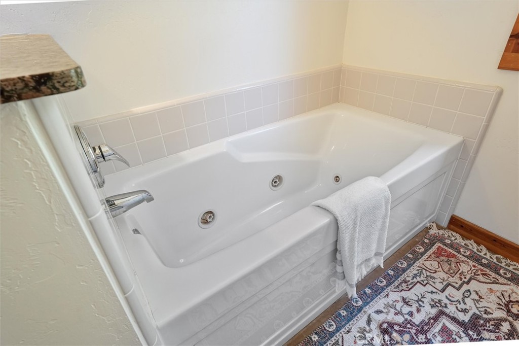 Jetted bathtub with pale tile surround, chrome fixtures, and a towel draped over the edge.