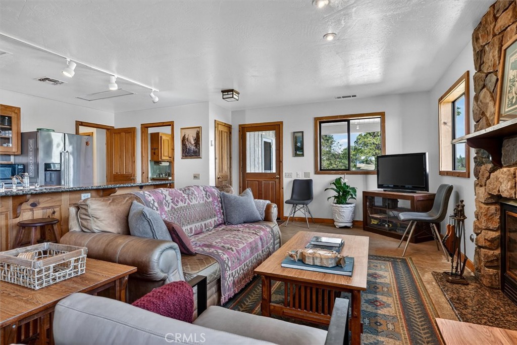 Living room with a stone fireplace, patterned sofa, and adjoining kitchen.