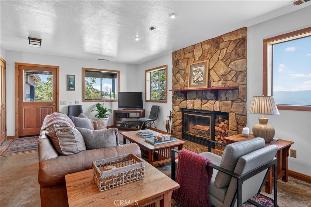Living room with a large stone fireplace, wood furnishings, and mountain views through the windows.