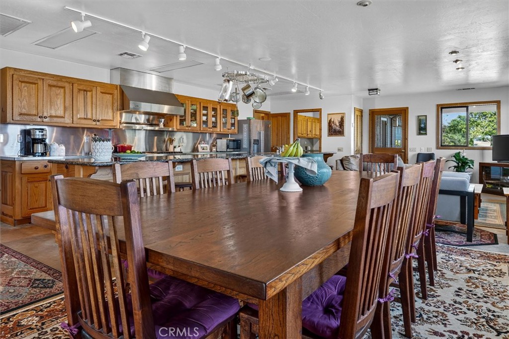 Dining area with a large wooden table, purple-cushioned chairs, and an adjoining wood-cabinet kitchen.