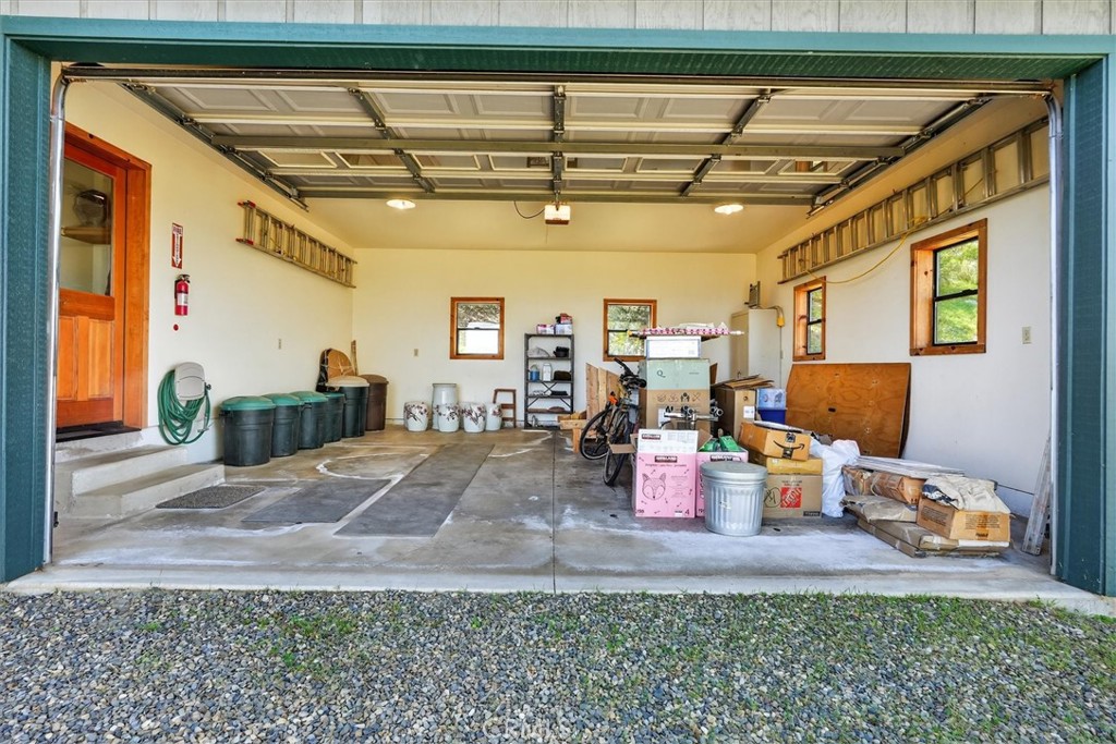 Open garage with storage bins, bicycles, ladders, and a concrete floor.