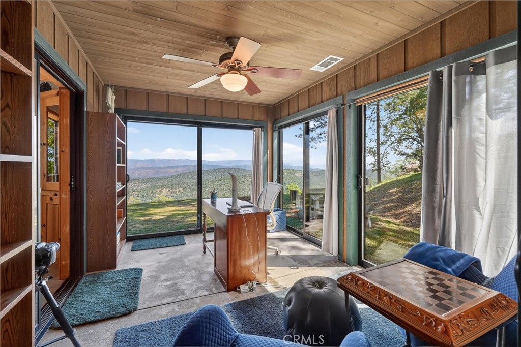 Wood-paneled office with large windows overlooking wooded hills and distant mountains.