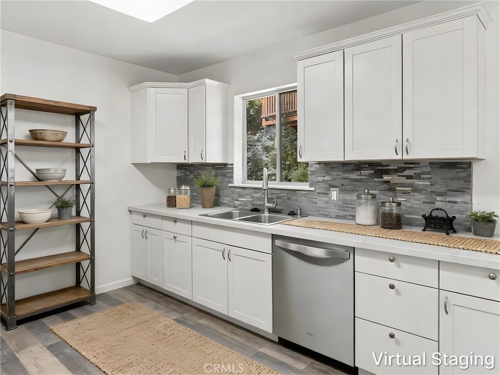 Kitchen with white cabinets, gray tile backsplash, double sink beneath a window, and open wood shelving.
