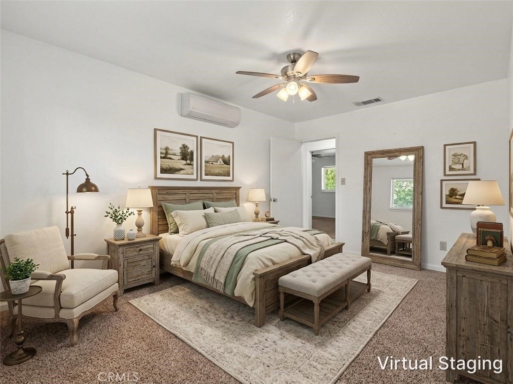 Bedroom with a wooden bed, upholstered bench, cream armchair, and ceiling fan.