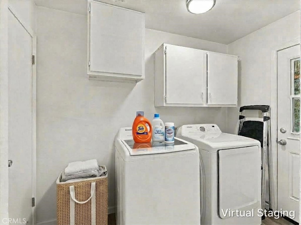 Laundry room with white washer and dryer, overhead cabinets, and a woven basket of towels.
