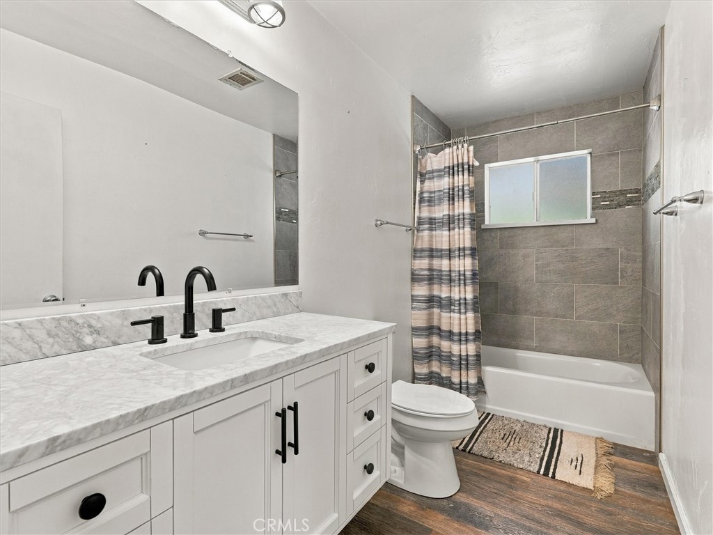 Bathroom with white vanity, black fixtures, gray-tiled tub surround, and striped shower curtain.