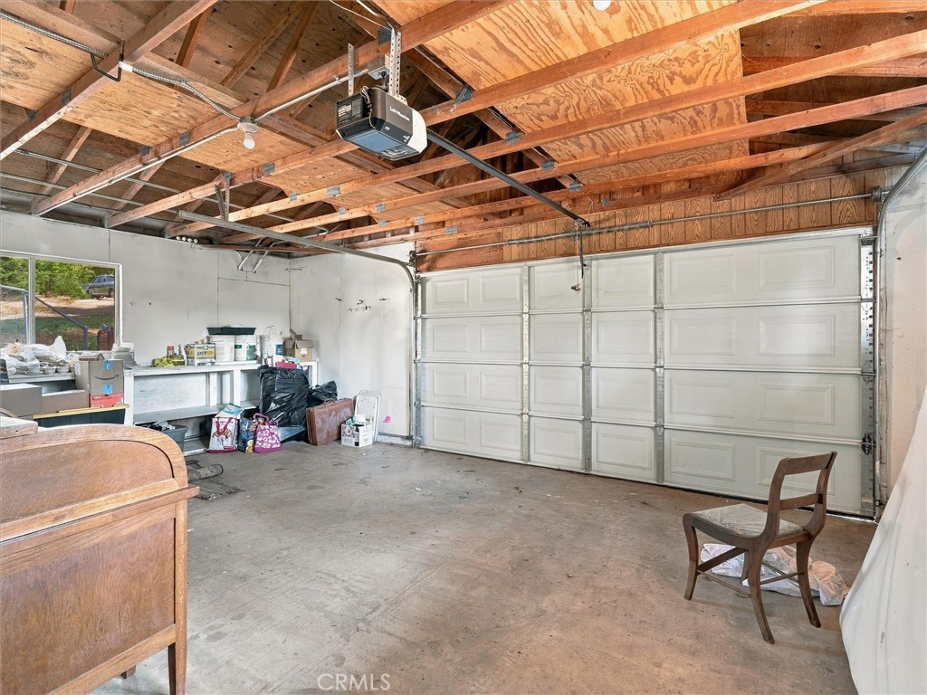 Garage with exposed wooden ceiling framing, a large sectional door, and a workbench along the wall.