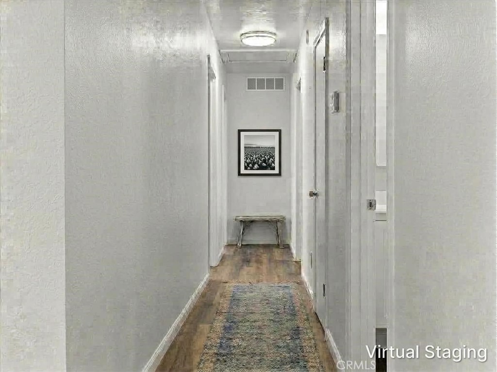 Hallway with wood floors, a patterned runner, and a console table beneath framed artwork.