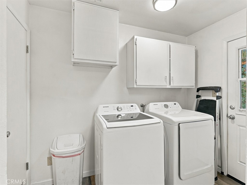 Laundry room with white washer and dryer beneath wall-mounted cabinets.