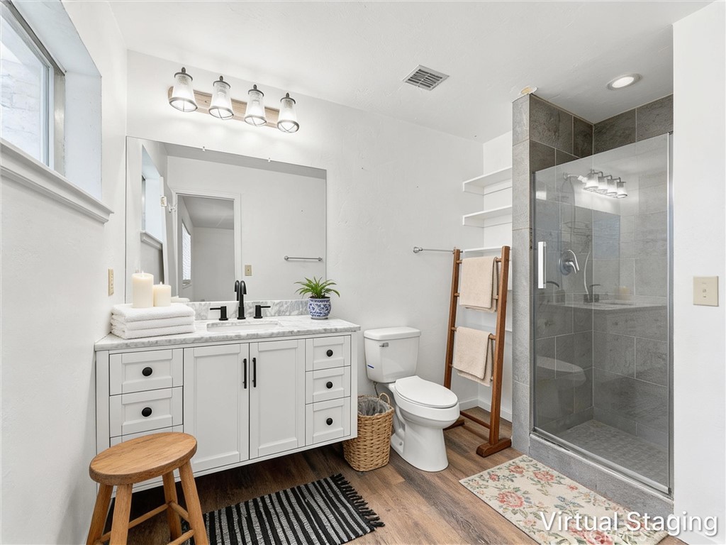 Bathroom with a white vanity, marble-look countertop, and glass-enclosed gray-tile shower.