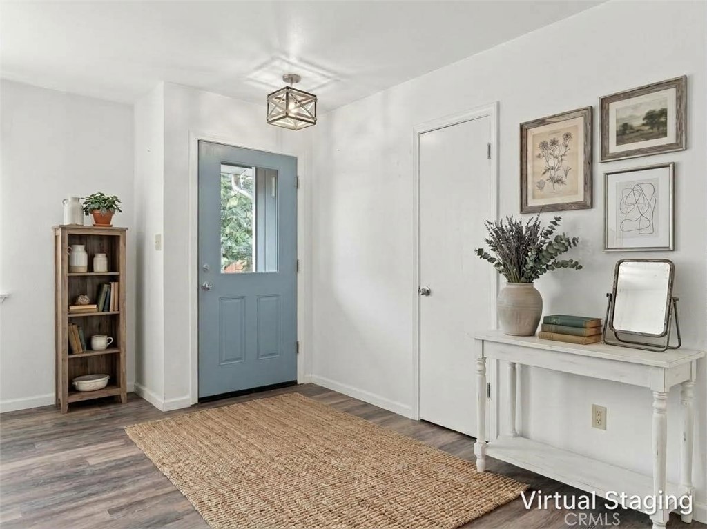 Entryway with a blue front door, woven rug, narrow bookcase, and white console table.