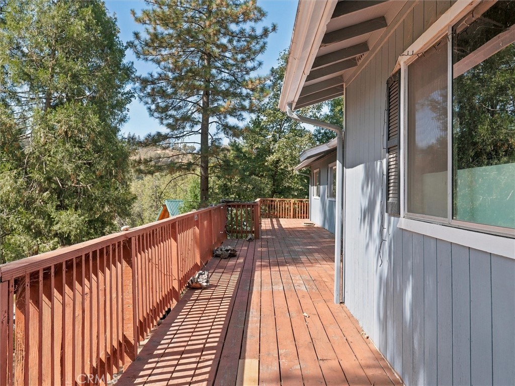 House-side deck with red railings overlooking mature trees.