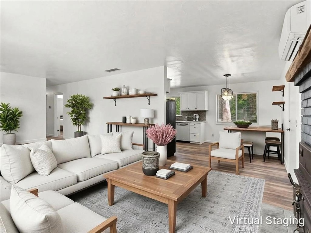 Virtually staged living room with a white sectional, wooden coffee table, and open kitchen and dining area.