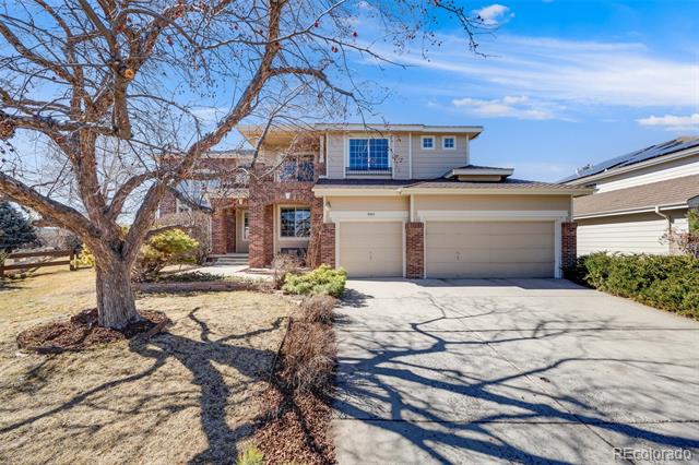 Two-story brick-and-siding home with an attached garage and a leafless tree beside the driveway.