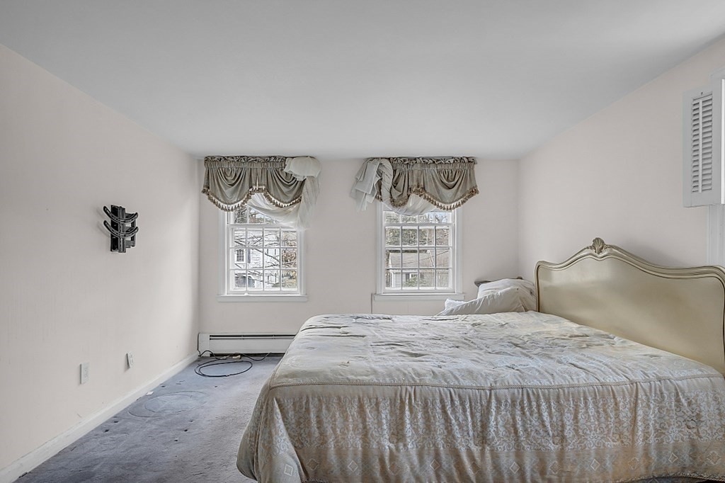 Bedroom with a large bed, patterned bedding, and two windows with decorative valances.