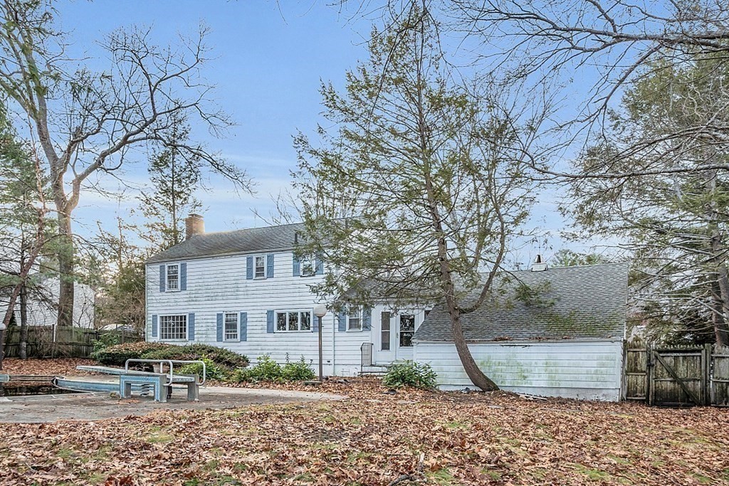 White two-story house with an attached garage, pool, and leaf-covered yard.