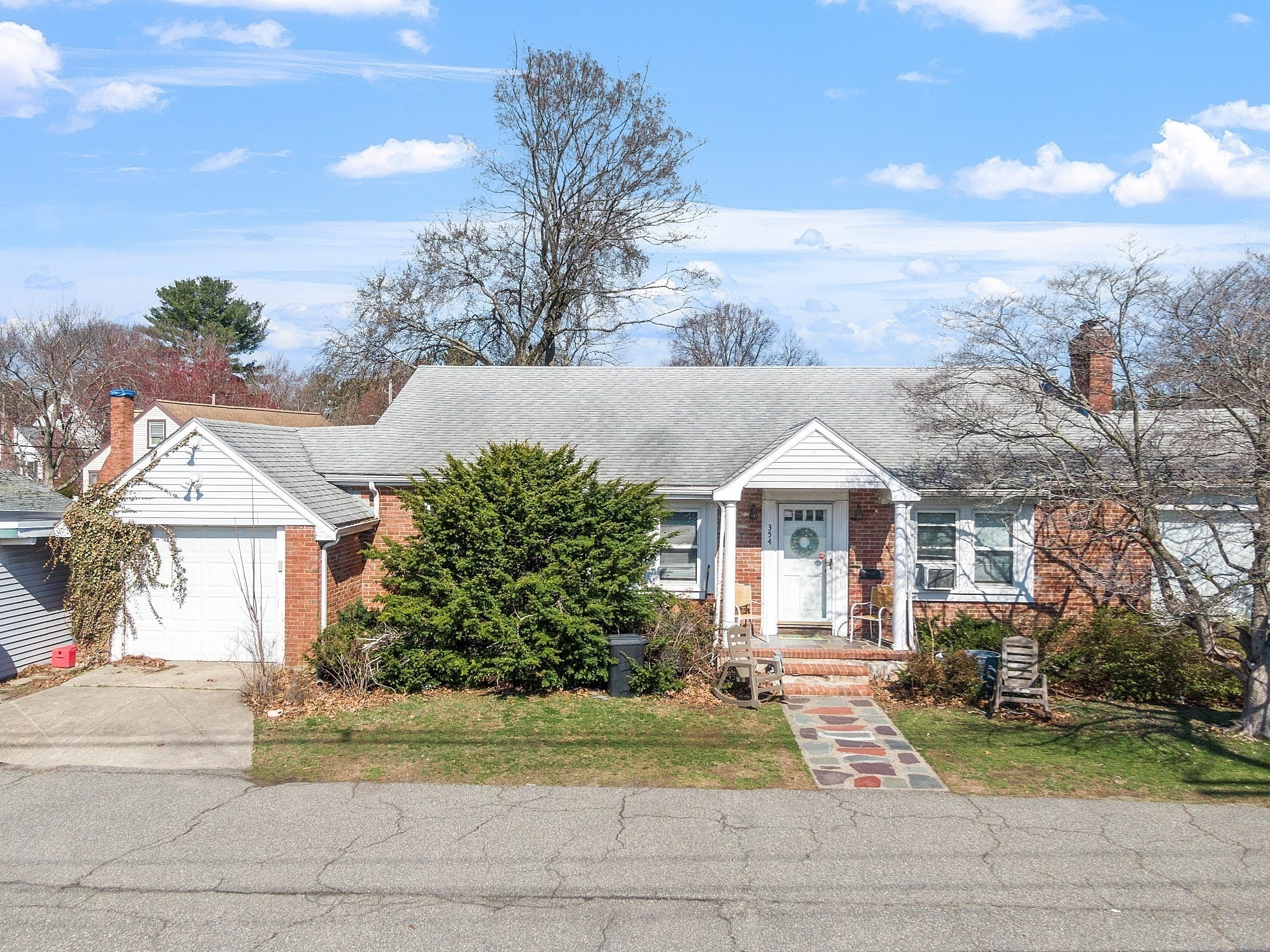Red-brick house with an attached garage, covered entry, and stone walkway.