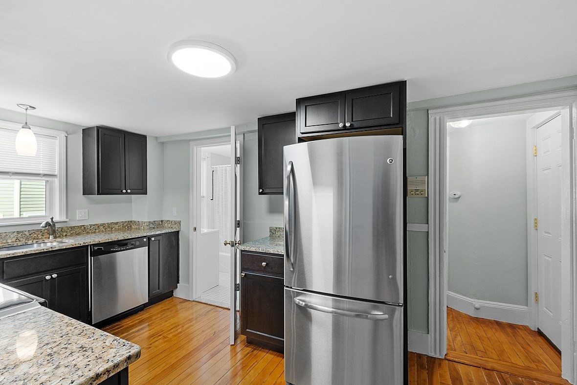 Kitchen with dark cabinets, granite countertops, stainless steel appliances, and hardwood floors.