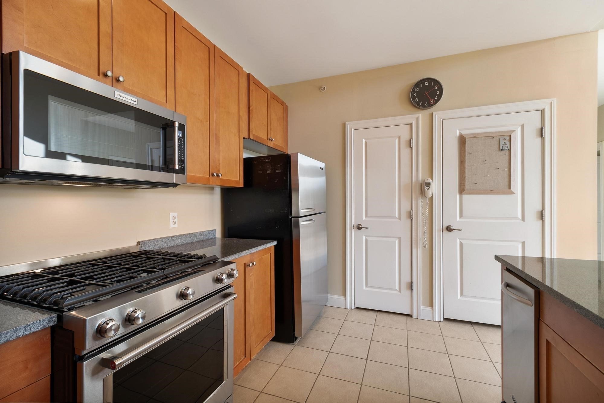 Kitchen with warm wood cabinets, granite counters, and stainless-steel appliances, including a gas range.