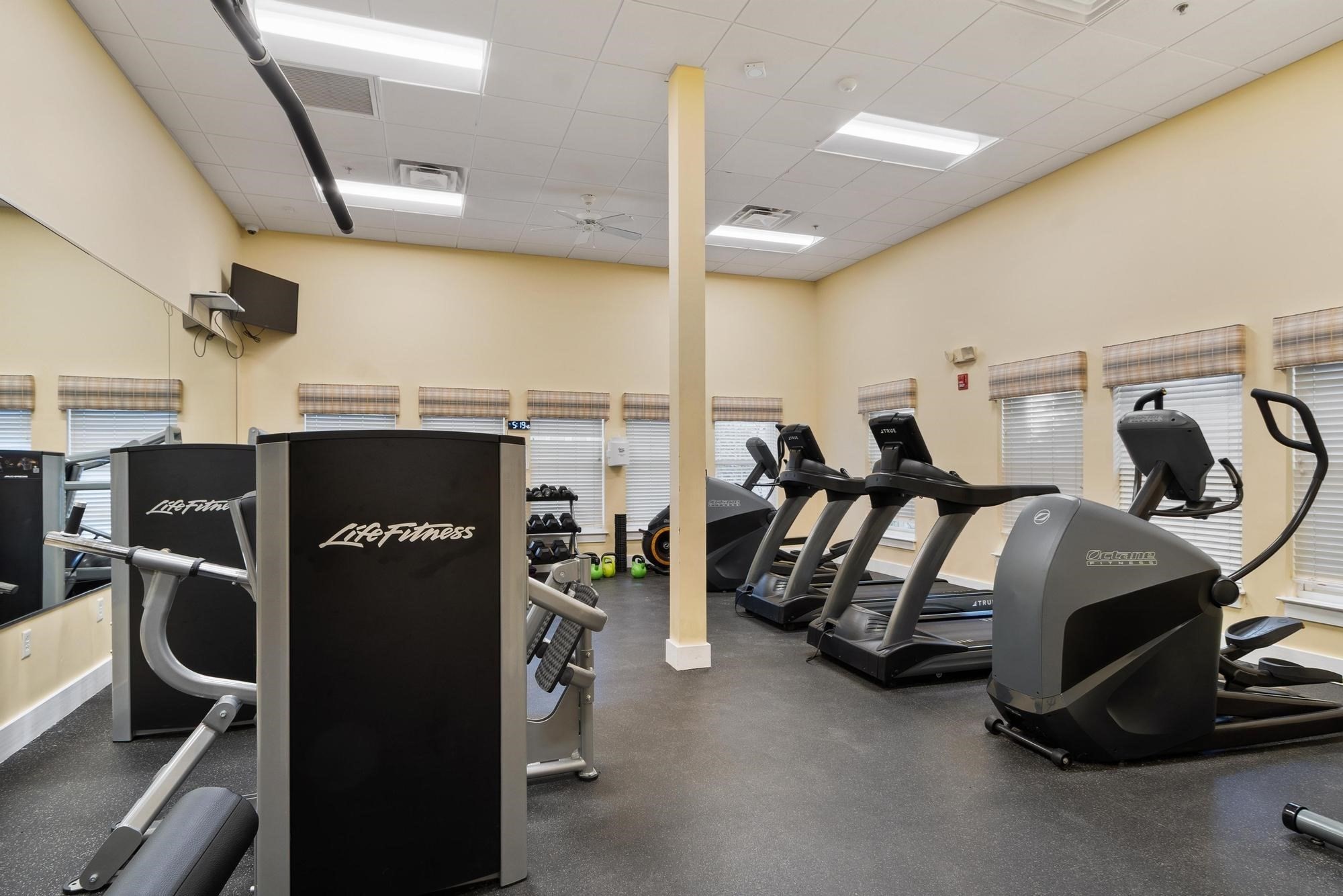 Fitness room with treadmills, elliptical machines, and weight equipment.