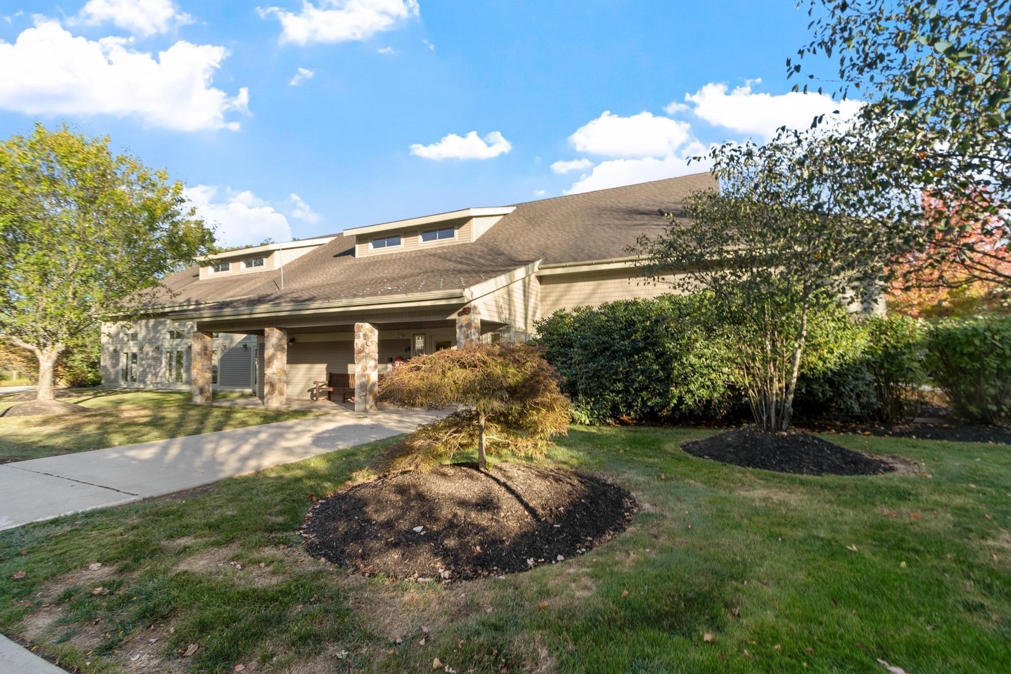 Condominium exterior with stone porch columns, dormer windows, and landscaped grounds.