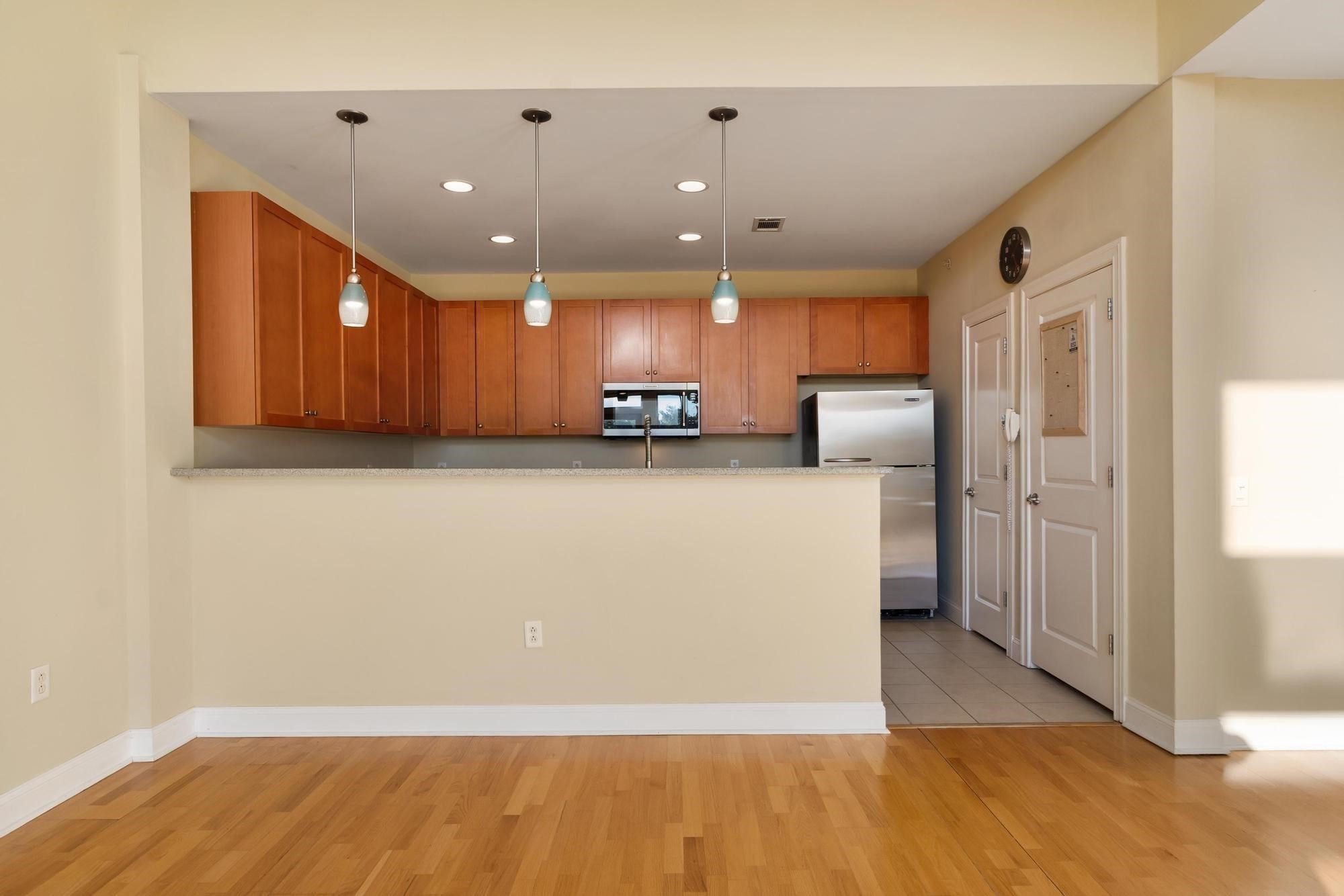 Unfurnished kitchen with warm wood cabinets, a breakfast bar, pendant lights, and stainless steel appliances.