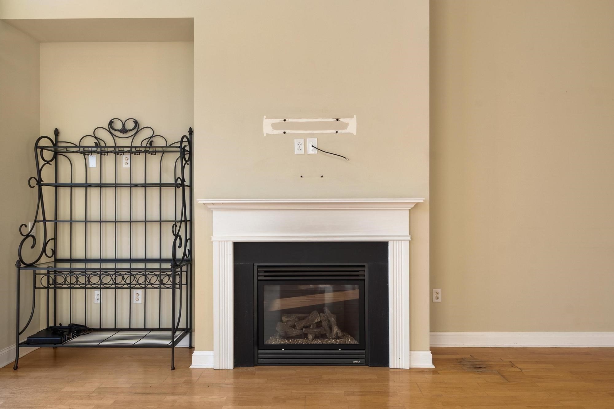 Unfurnished living room with a white-trimmed gas fireplace and black metal shelving.