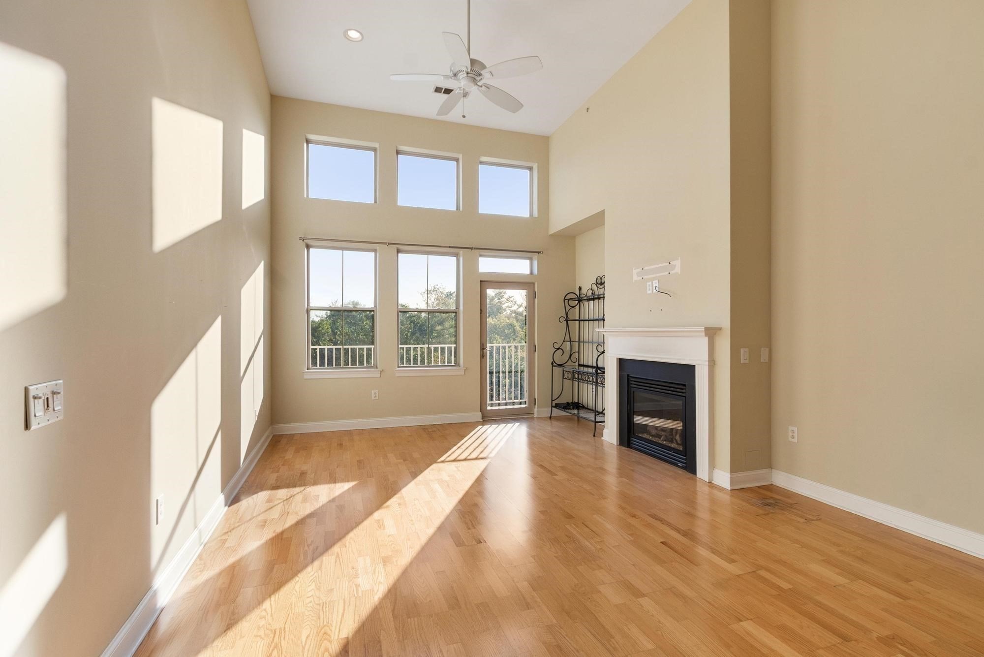 Living room with vaulted ceiling, hardwood floors, tall windows, and a gas fireplace.