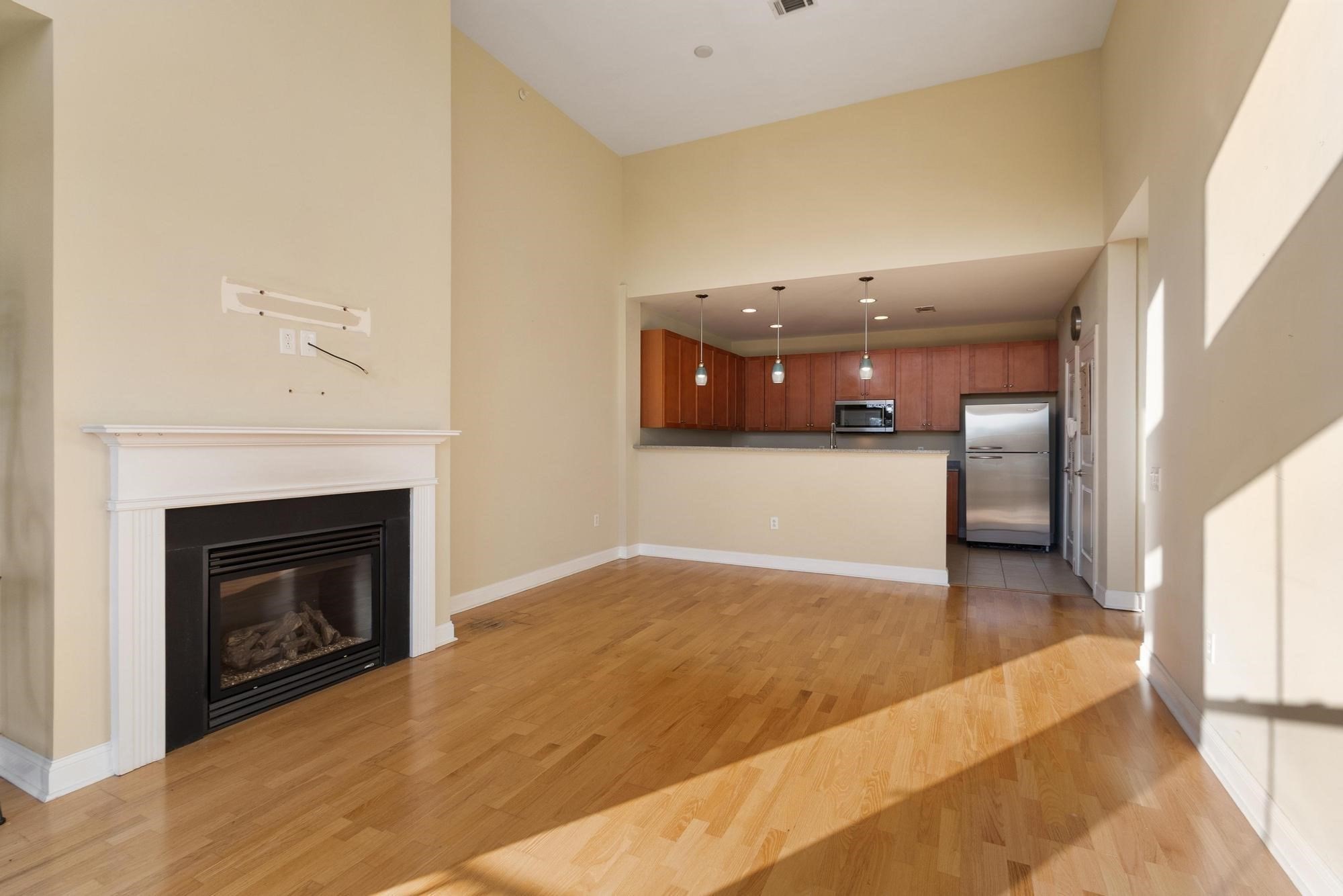 Open living area with hardwood floors, gas fireplace, and a kitchen with cherry cabinets and stainless steel appliances.