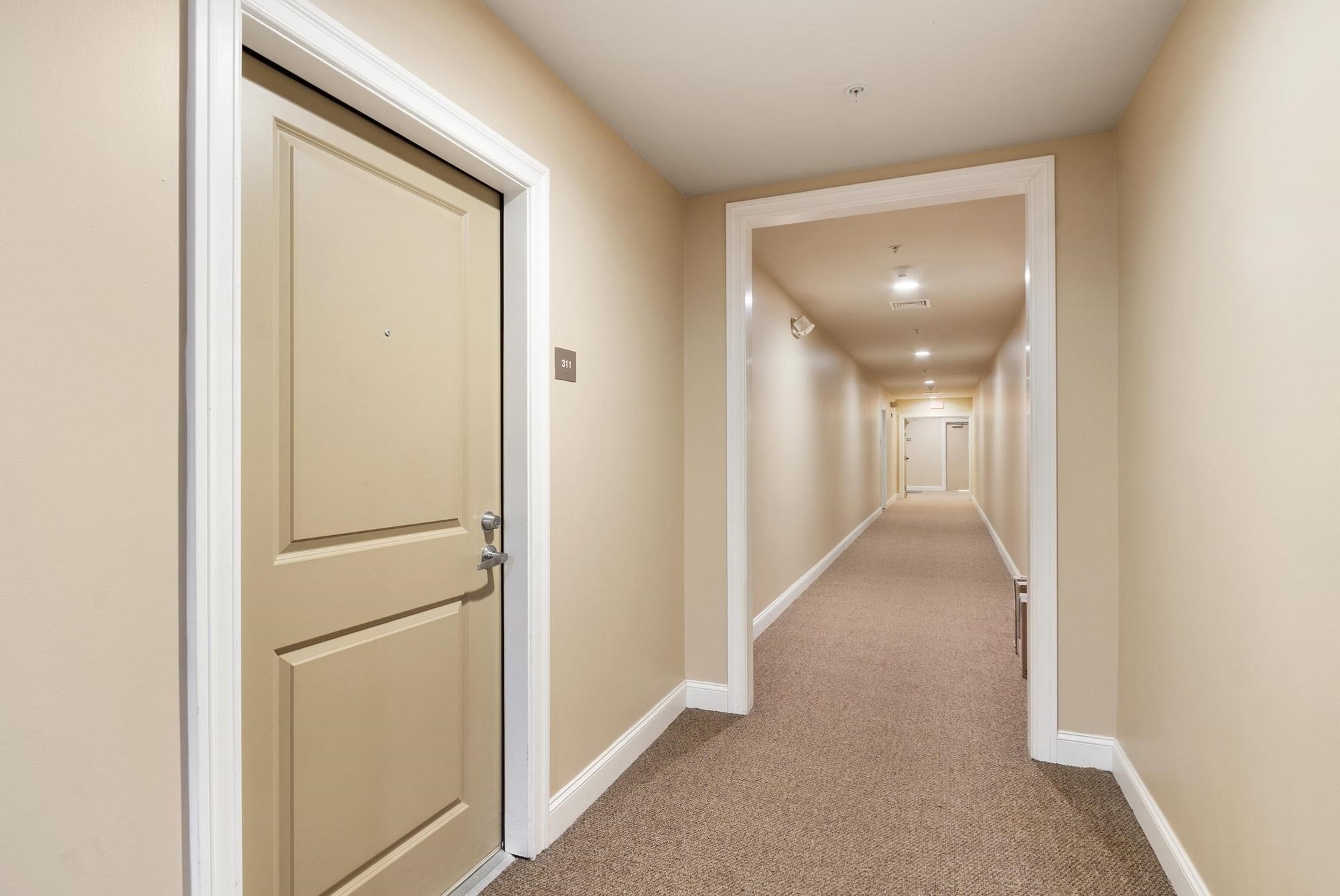 Apartment hallway with a beige paneled door marked 311 and carpeted corridor.