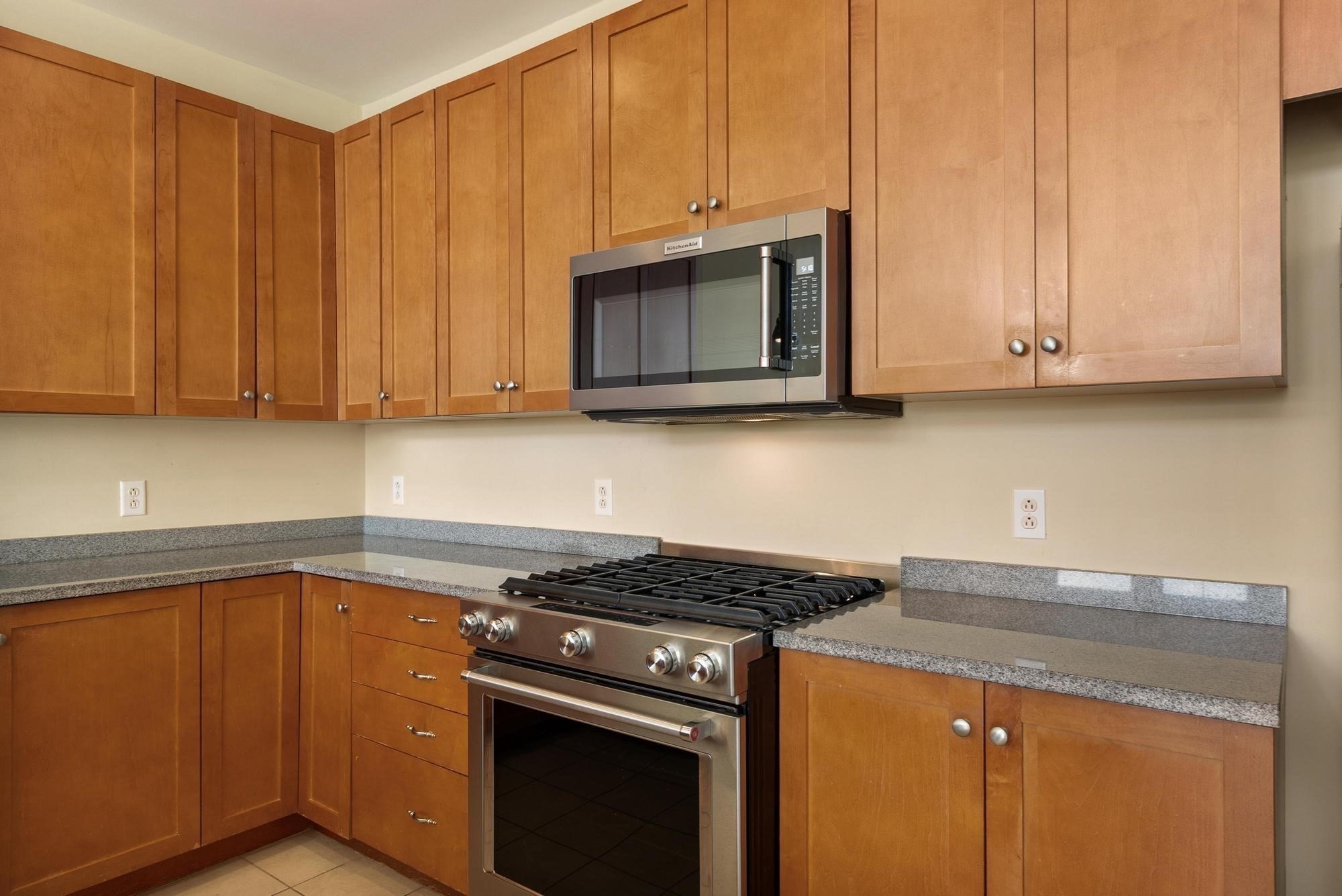 Kitchen with honey-toned cabinets, granite countertops, and a stainless steel gas range.