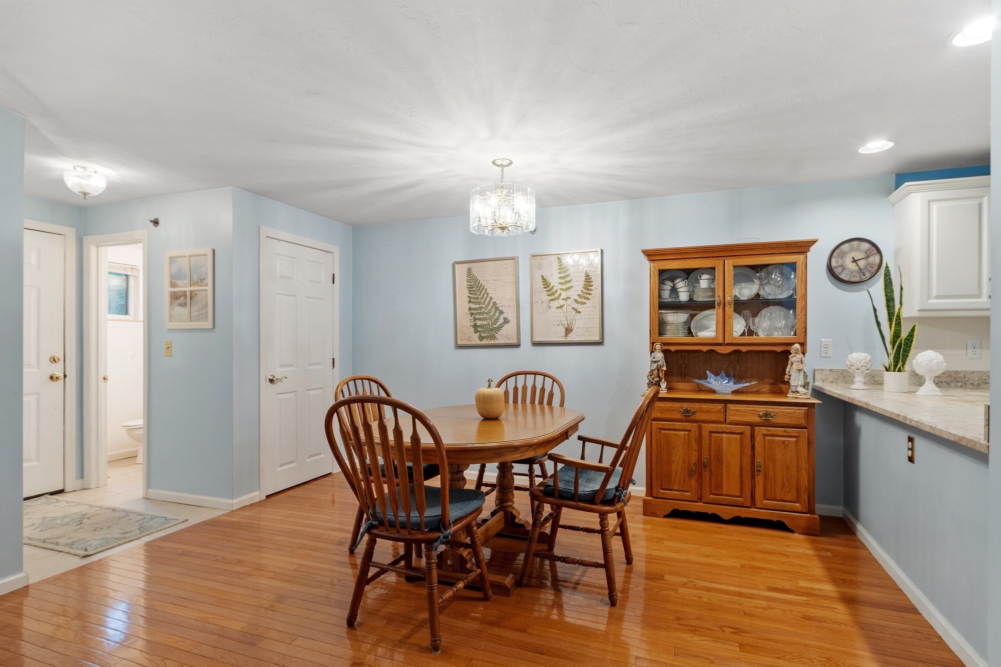 Dining room with a wooden table, glass-front china cabinet, and polished hardwood floors.