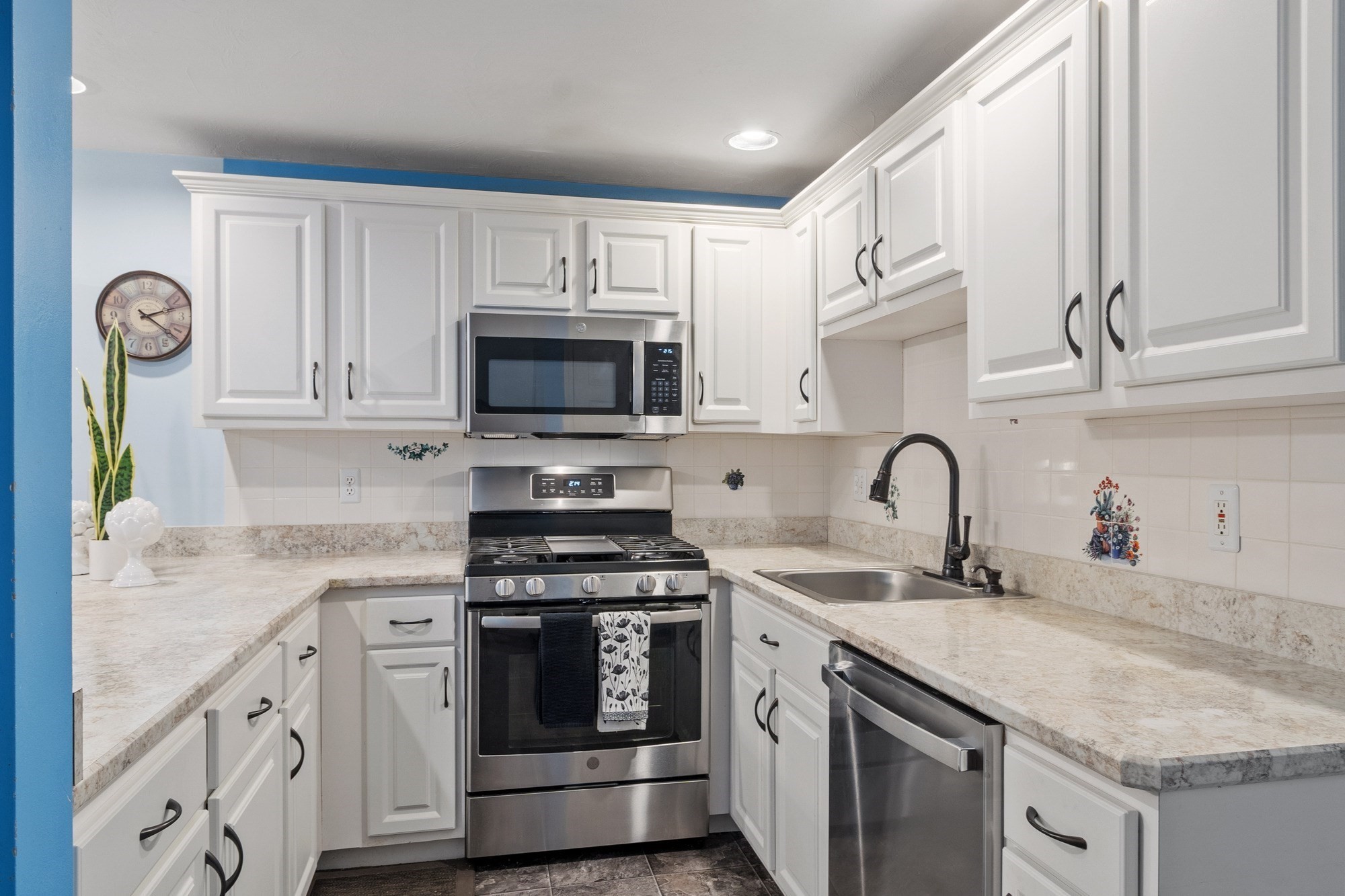 Kitchen with white cabinets, stone counters, and stainless steel appliances.