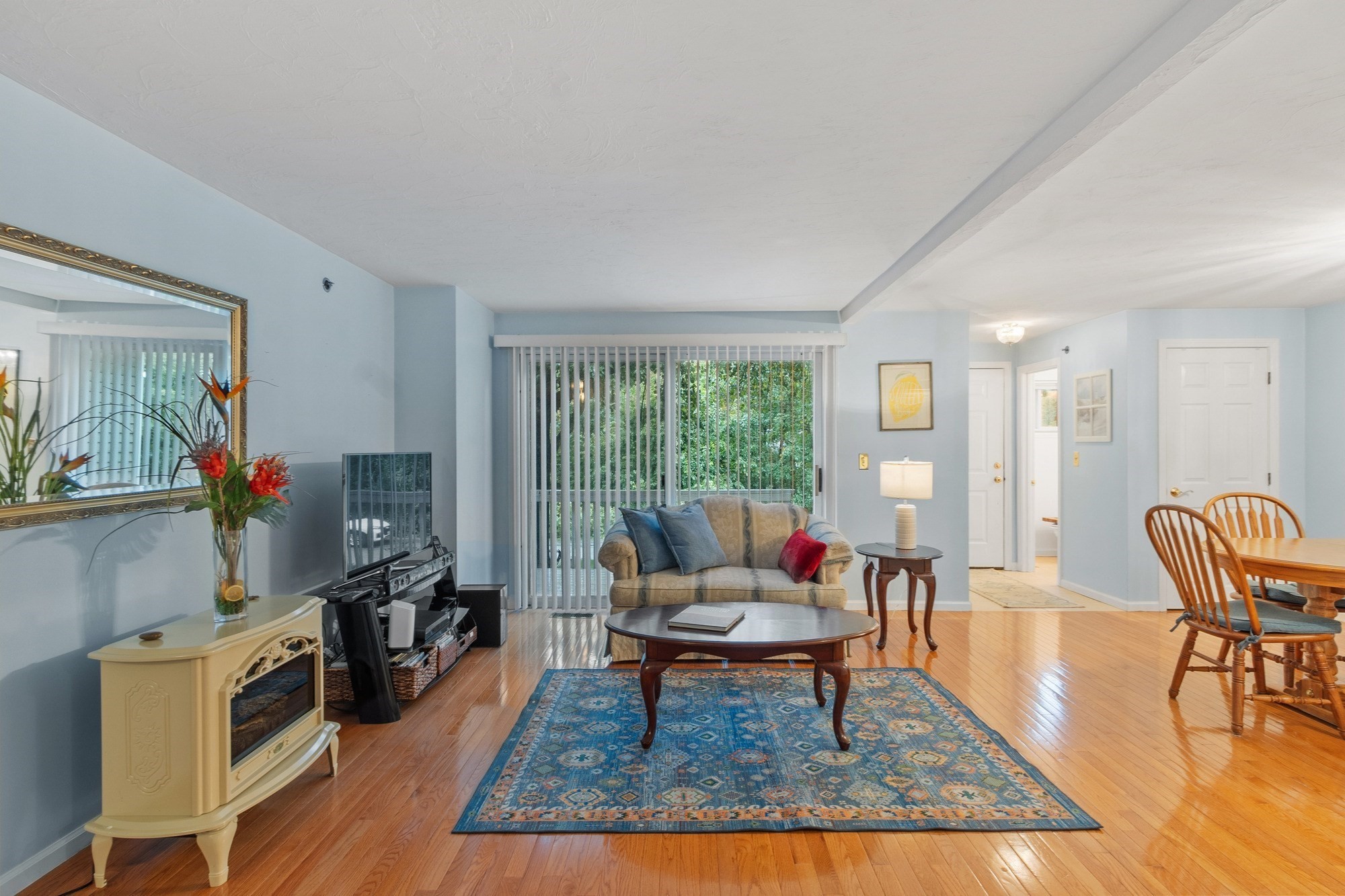 Living room with a sofa, blue patterned rug, hardwood floors, and dining area.