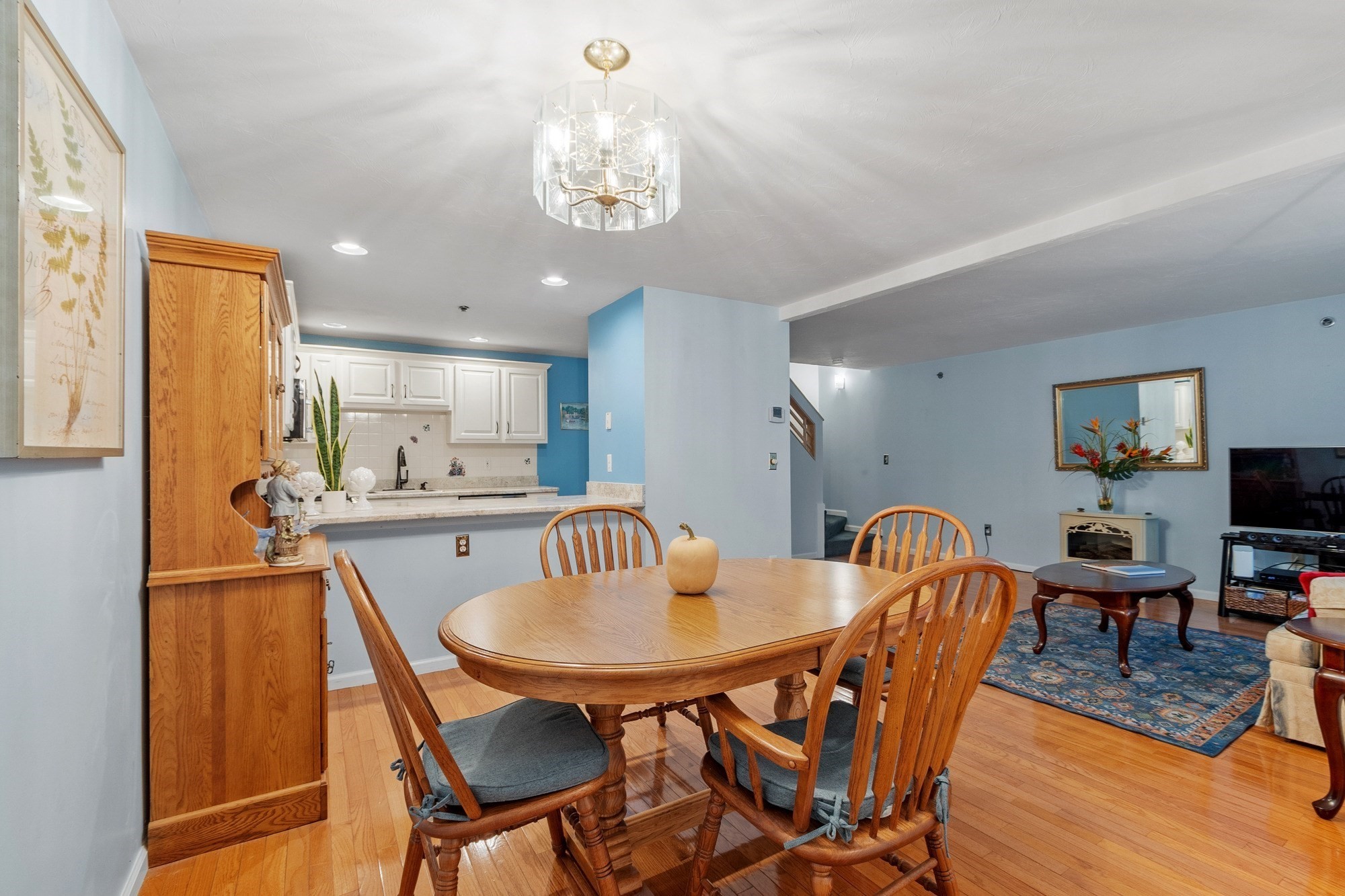 Dining area with a wood table and chairs beside an open kitchen and living room.