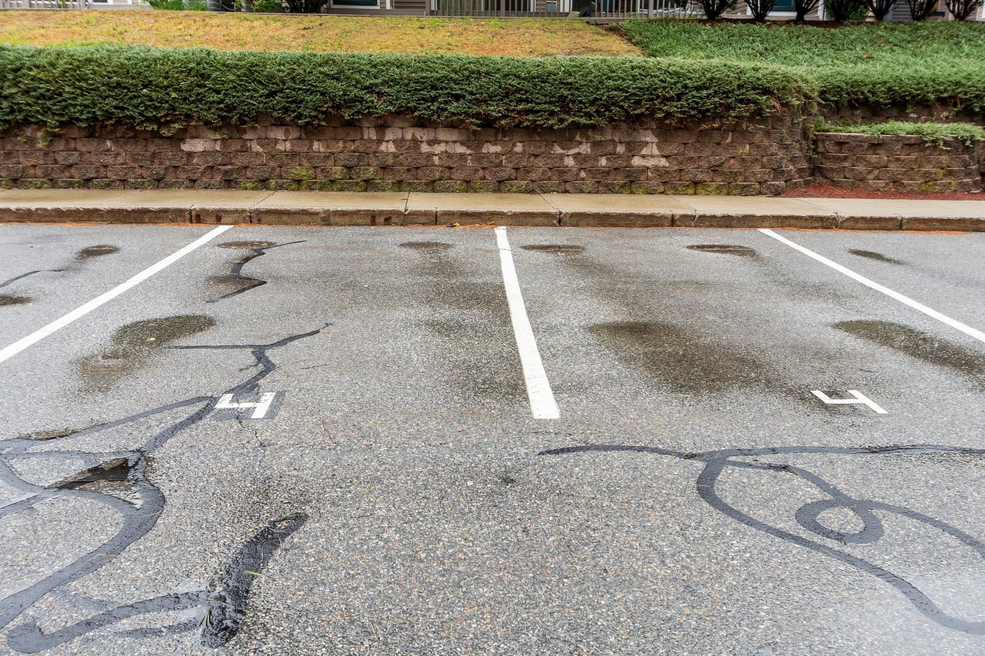 Parking spaces 4 and 5 beside a stone retaining wall and trimmed hedge.