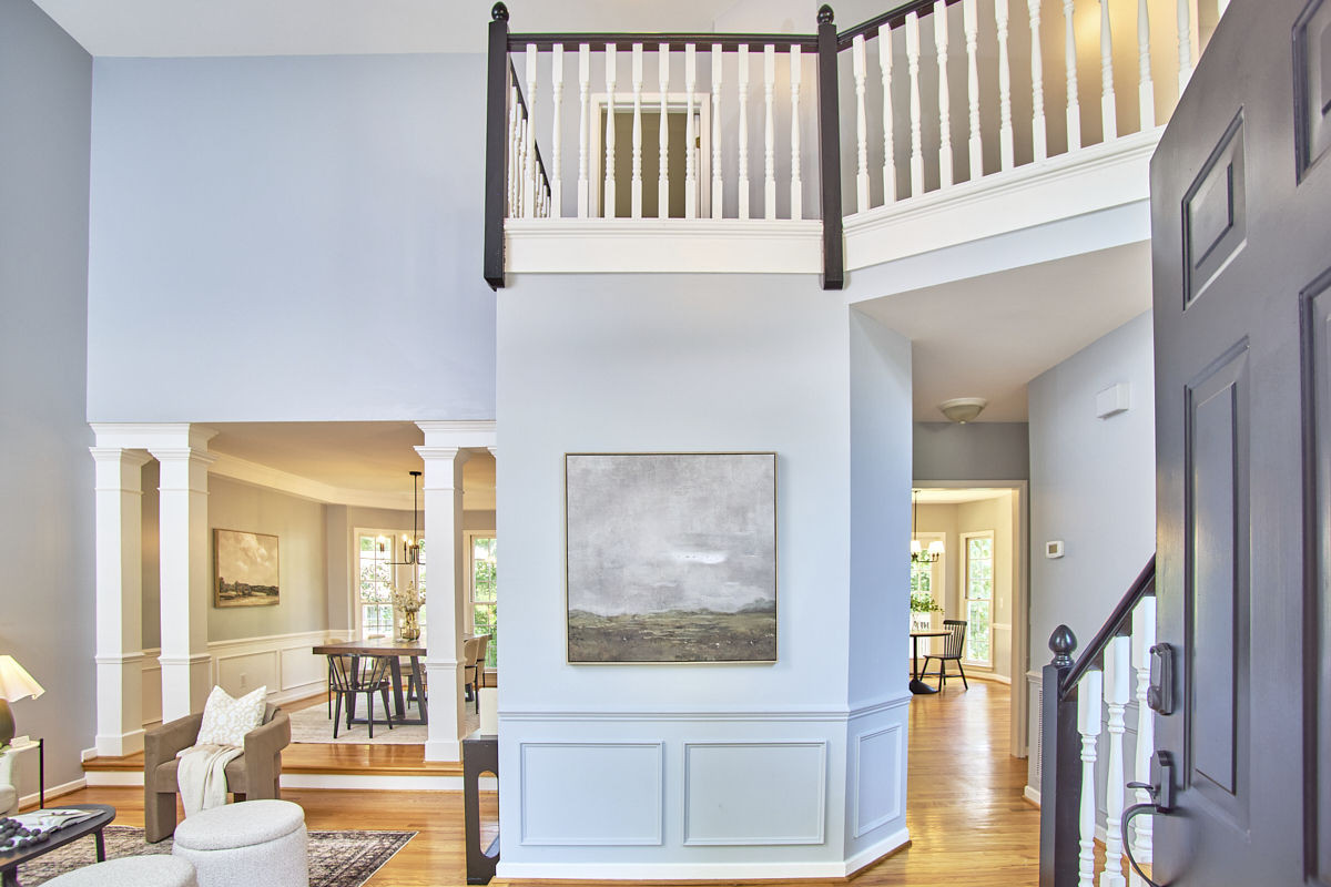 Two-story entry foyer with hardwood floors, an upper-level railing, and open views into living and dining areas.