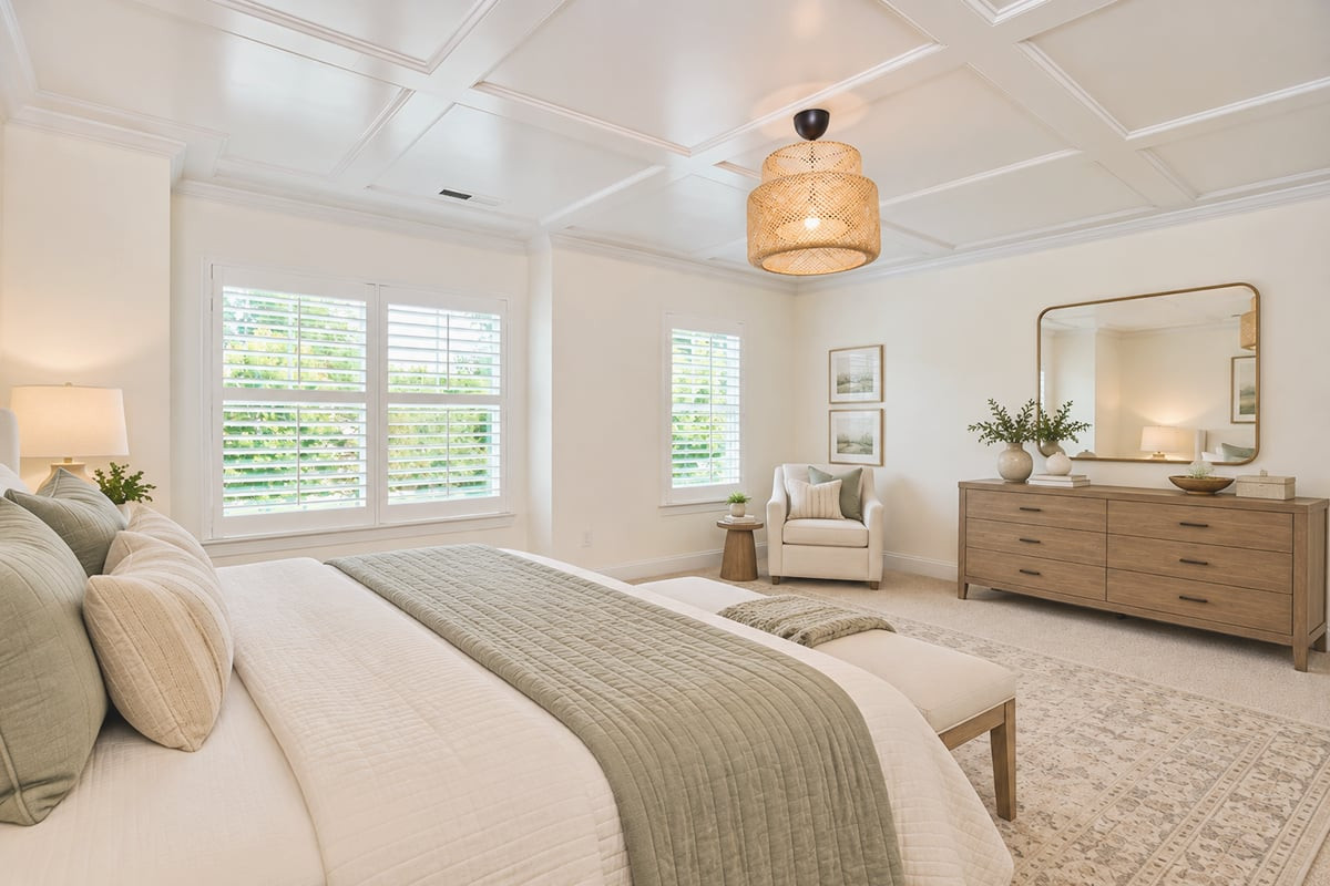 Staged bedroom with a large sage-and-white bed, shuttered windows, and coffered ceiling.