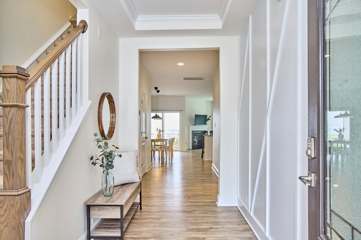 Entry hallway with wood floors, a carpeted staircase, and views into the dining and living areas.