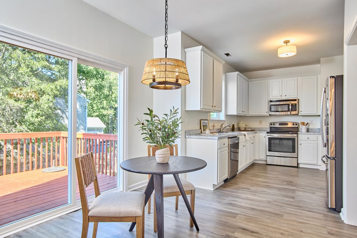 Bright kitchen with white cabinetry, stainless appliances, and sliding doors to a wood deck.