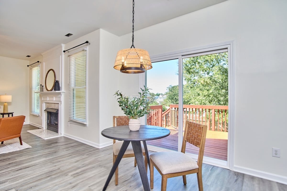 Dining area with a round table beside sliding doors opening onto a deck; fireplace visible nearby.