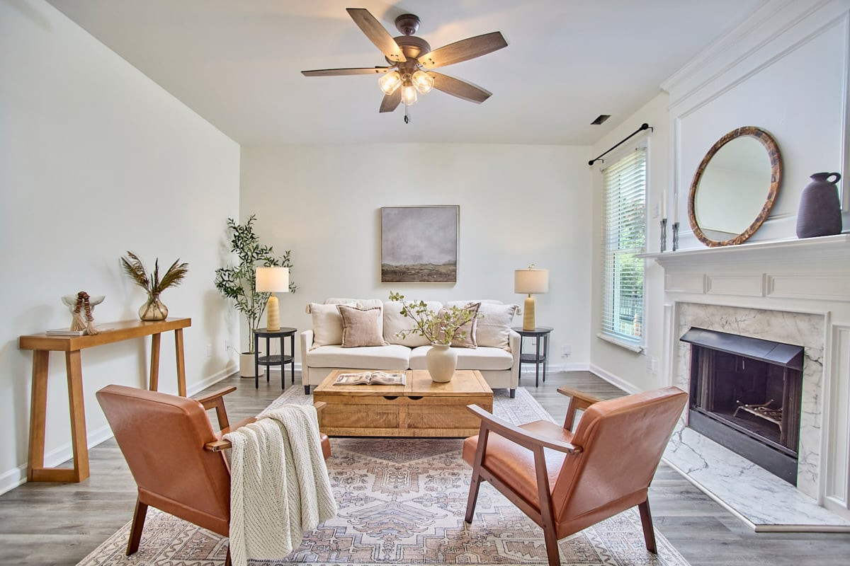 Living room with a white sofa, leather chairs, and a marble fireplace.