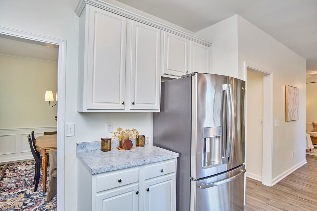 Kitchen with white cabinetry, a stone counter, and a stainless steel refrigerator.