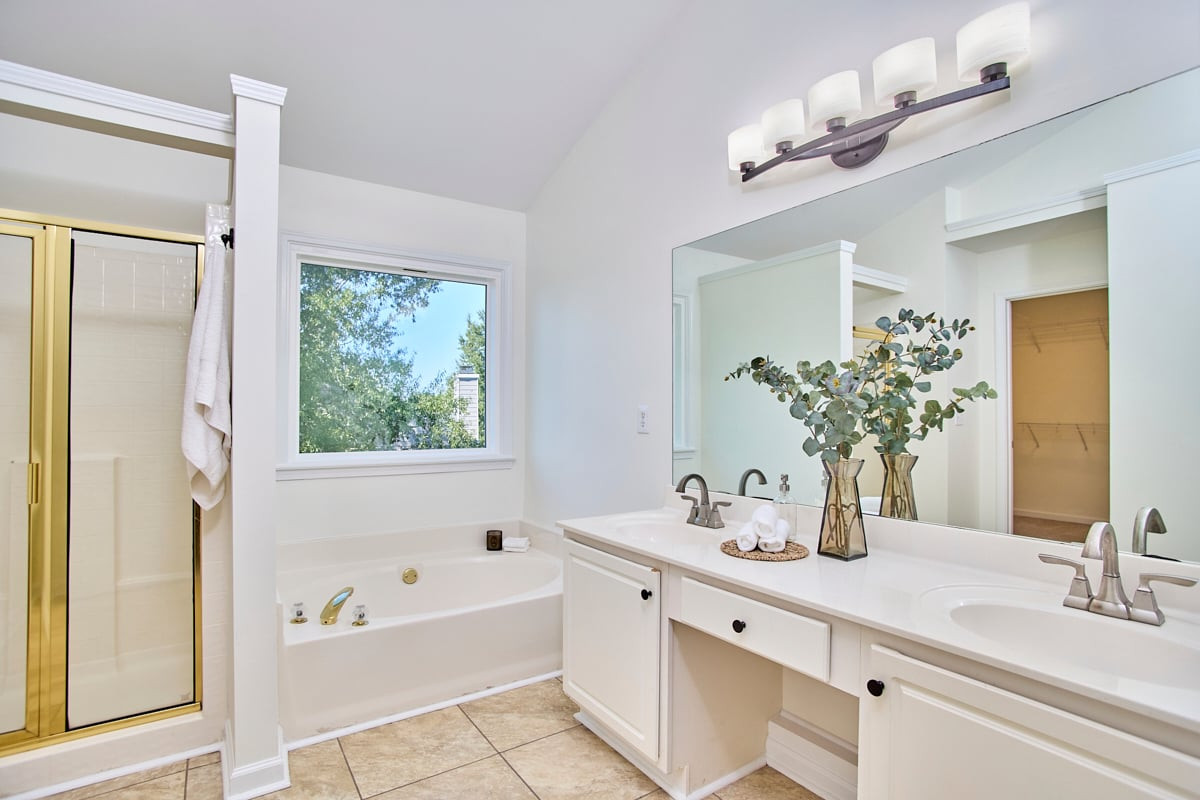 Bathroom with a soaking tub, glass shower, and long double-sink vanity.