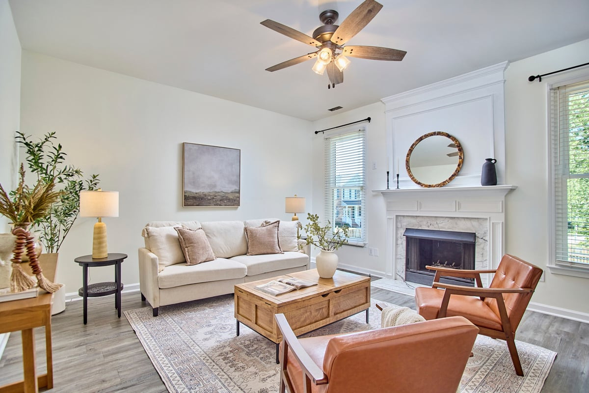 Living room with a fireplace, cream sofa, leather chairs, and wood coffee table.