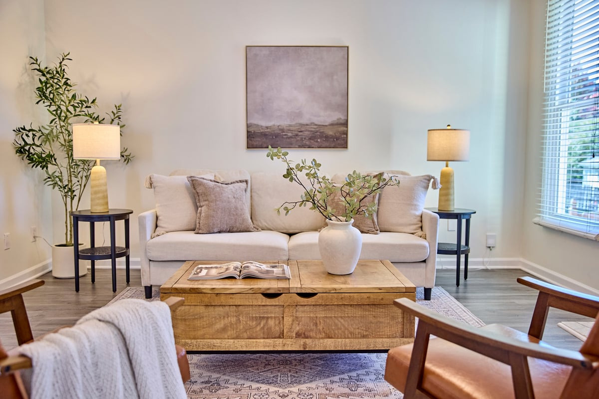Staged living room with a cream sofa, wooden coffee table, and large window.