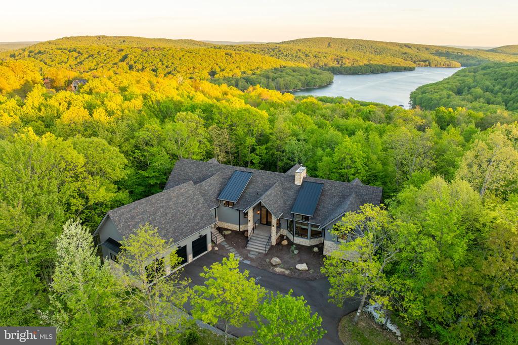 Aerial view of a woodland home with a river beyond the trees.