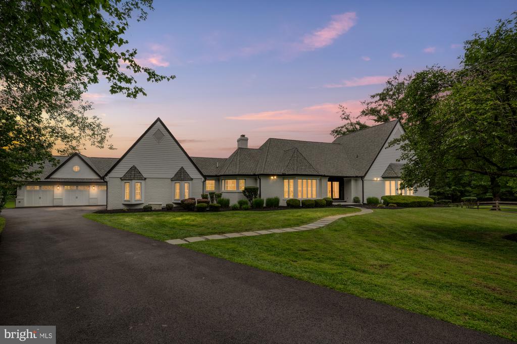 Gray gabled home with a two-car garage and curved walkway at dusk.