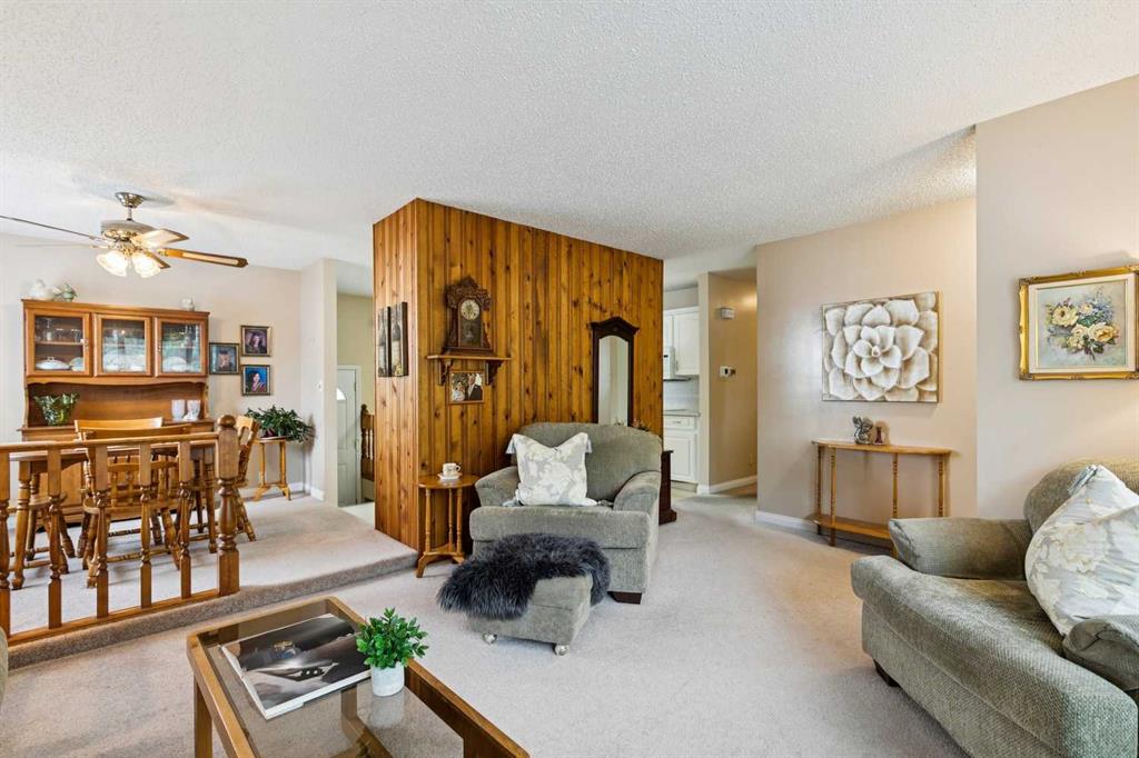 Living room and dining area with a wood-paneled divider and furnished seating.